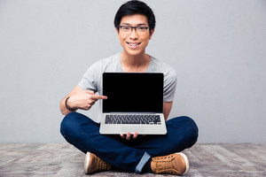 smiling-asian-man-showing-finger-on-laptop-screen_thumb