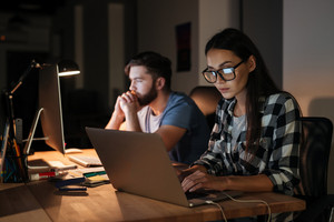 graphicstock-image-of-two-business-people-working-with-laptop-and-computer-late-at-night-in-their-office_HILxdmO2l_thumb